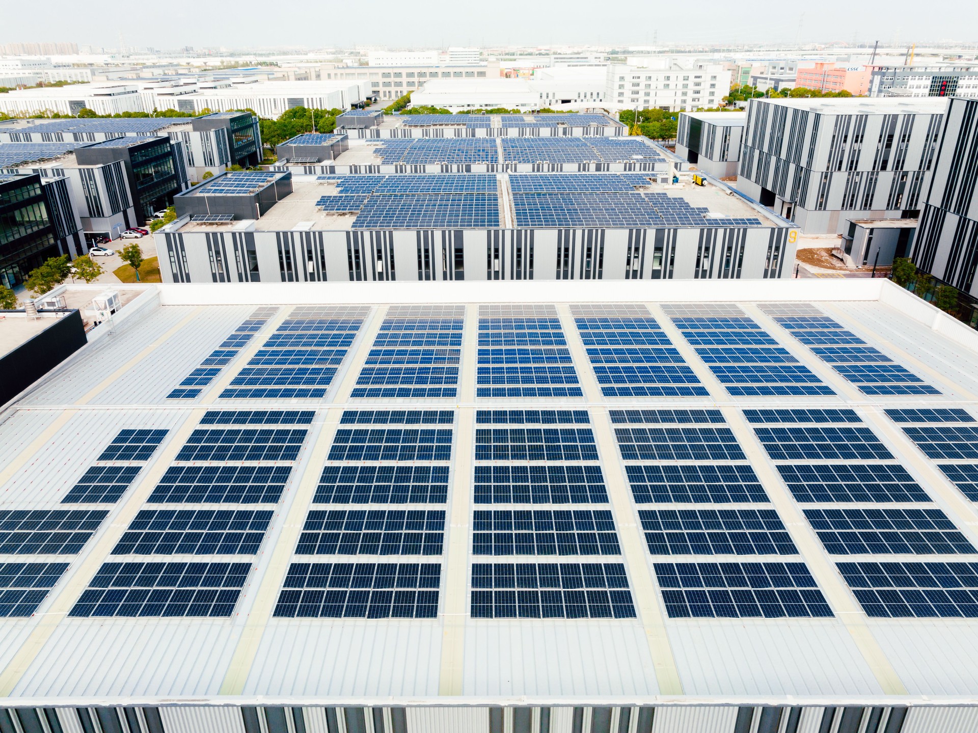 Aerial view of solar panels on factory roof. Blue shiny solar photo voltaic panels system product.